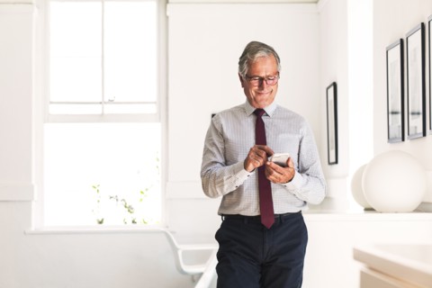 Smiling Caucasian businessman texting on cell phone