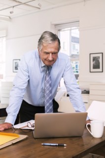 Caucasian businessman leaning on table using laptop