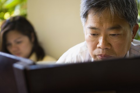 Mature Asian man reading book