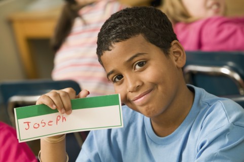 Mixed race school boy holding name card