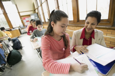Hispanic school teacher helping student