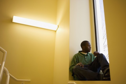African teenager sitting in window sill