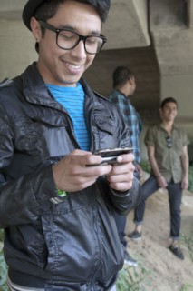 Smiling mixed race teenage boy text messaging with cell phone