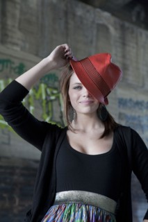 Smiling Caucasian teenage girl tipping hat on head