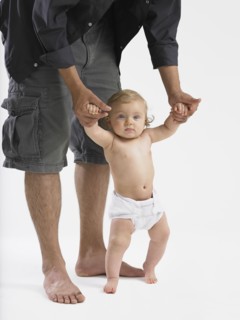 Mixed race father helping baby girl learn to walk