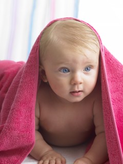 Mixed race baby girl laying under towel