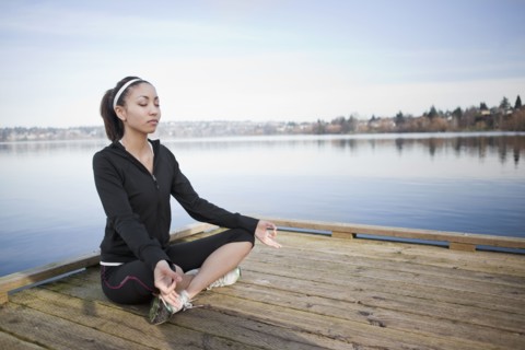 Mixed race woman practicing yoga on pier