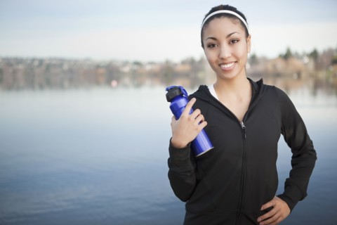 Mixed race woman near lake holding water bottle