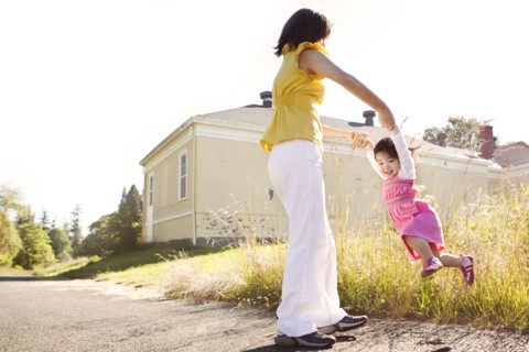 Chinese mother swinging daughter outdoors