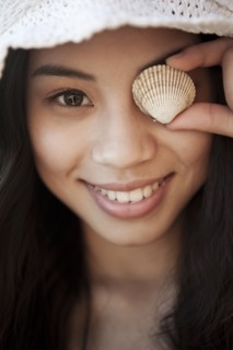 Smiling Chinese woman with shell in front of her eye