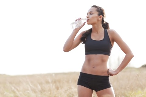 Serious woman in sportswear drinking water