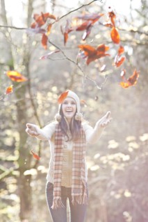 Mixed race woman in cap playing in autumn leaves