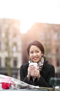 Mixed race woman holding coffee with bouquet of flowers