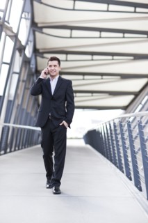 Mixed race businessman walking and talking on cell phone