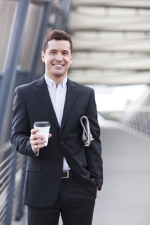Mixed race businessman carrying coffee and newspaper