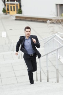 Mixed race businessman running up stairs