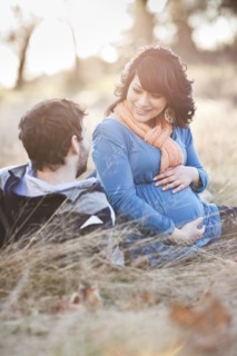 Pregnant woman sitting in field with husband