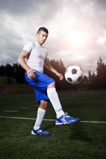 Hispanic athlete kicking soccer ball
