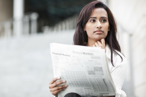 Indian businesswoman reading newspaper outdoors
