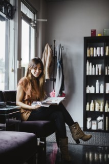 Mixed race woman reading magazine in salon