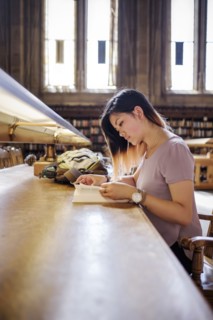 Chinese woman sitting in library reading book