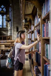 Chinese woman standing in library choosing book