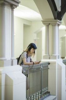 Chinese woman leaning on railing texting on cell phone