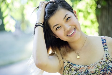 Portrait of smiling Chinese woman with hand in hair