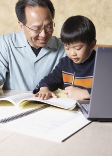 Asian father helping young son with homework