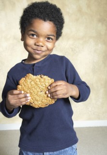 Young African American boy eating large cookie
