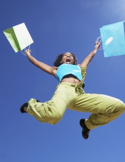 African woman holding shopping bags and jumping