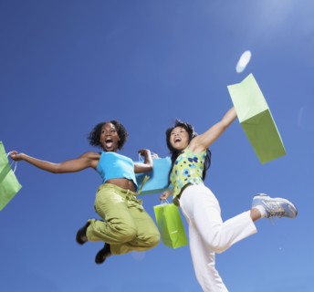 Two women holding shopping bags and jumping