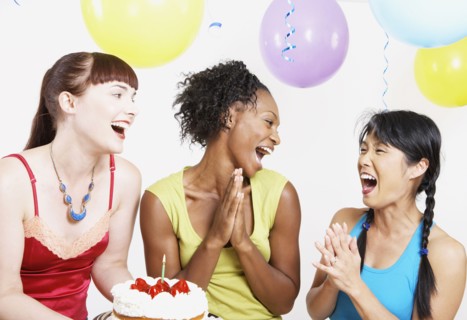 Three women laughing with cake at party
