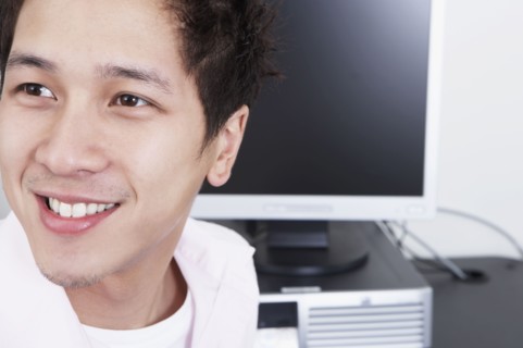 Close up of young Asian man next to computer