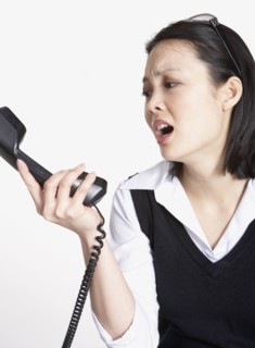 Studio shot of Asian businesswoman yelling at telephone