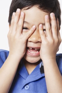 Young boy covering face with hands