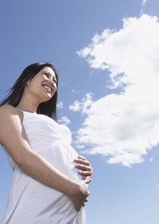 Low angle view of pregnant Asian woman under blue sky