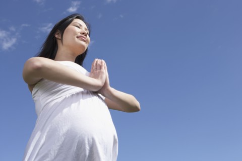 Pregnant Asian woman doing yoga outdoors