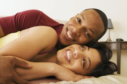 African couple hugging on bed