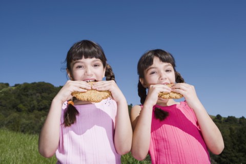 Young Hispanic sisters eating cookies outdoors