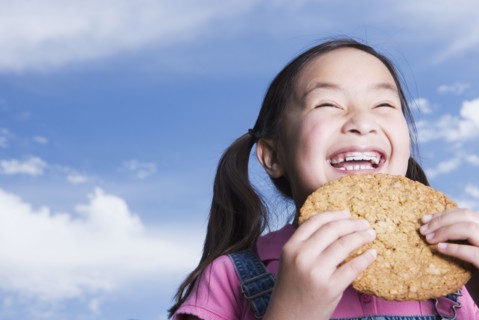 Young Asian girl holding cookie outdoors