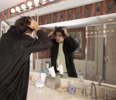 Hispanic man looking in bathroom mirror