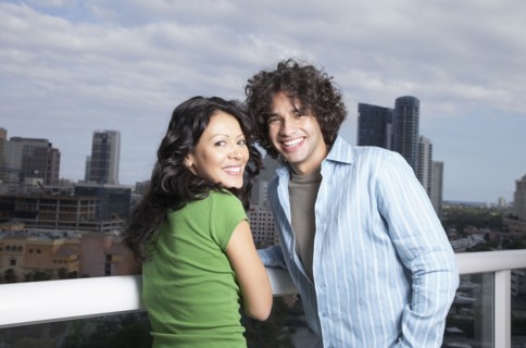 Hispanic couple leaning against balcony railing