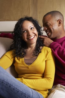 Multi-ethnic couple hugging on sofa