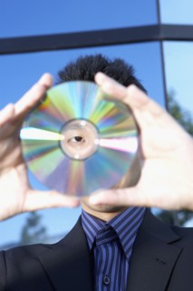 Asian businessman looking through center of cd