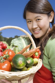 Asian woman holding basket of fresh vegetables
