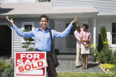 African American real estate agent and couple in front of new house