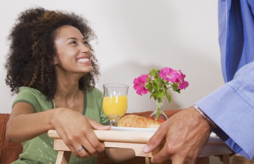 African man bringing breakfast in bed to wife