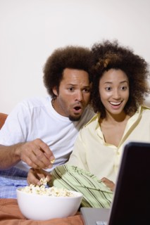 African couple watching movie on laptop