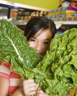 Asian girl holding green leaf vegetables